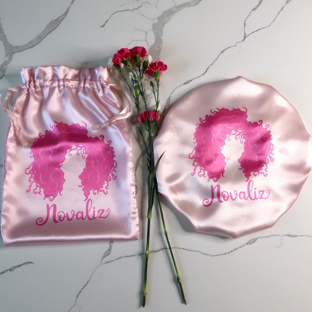 baby pink silky satin bonnet with matching satin bag with dark pink logo of curly girl